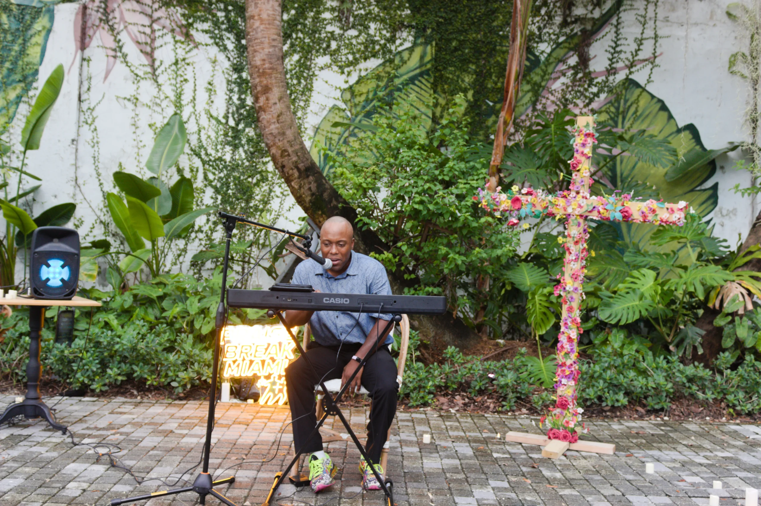 Keyboardist leading live worship beside a flower-covered cross